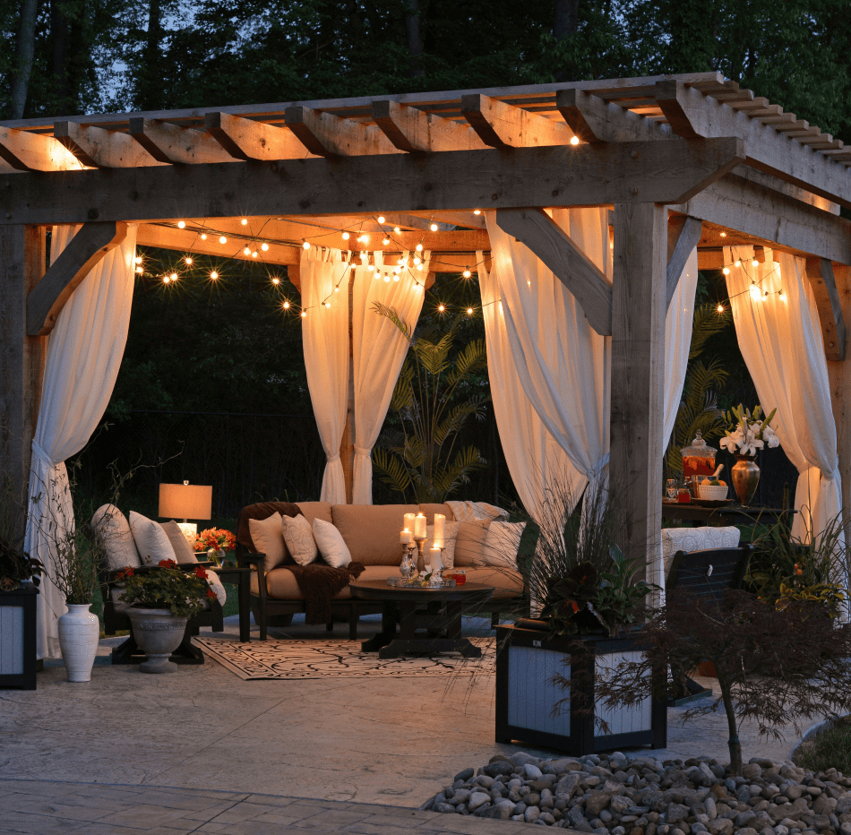 An outdoor patio pavilion at dusk with string lighting, candles and outdoor seating.